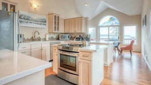 A modern kitchen with a central island, stainless steel appliances, and wooden cabinetry. - Lakefront Estate w/ Private Beach on Flathead Lake (Lakeside)