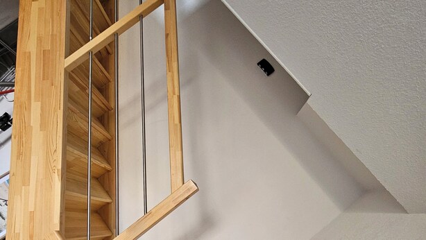 A modern staircase with wooden steps and metal railings, leading to a white wall with a small black object on it. - Duplex apartment Mimizan plage (Mimizan)