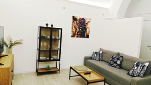 Ein modernes Wohnzimmer mit einem grauen Sofa, einem Holztisch und einer schwarzen Kommode mit Glastüren.