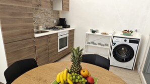 Eine kleine Küche mit Holzausstattung, einem Gasherd, einer Kaffeemaschine und einer Waschmaschine.