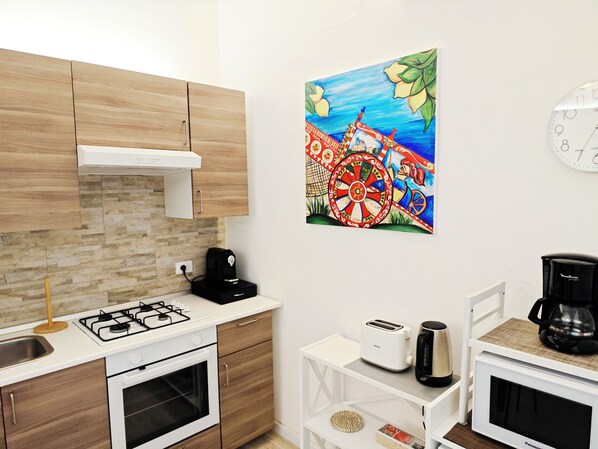 A modern kitchen with wooden cabinets, a gas stove, a toaster, and a coffee maker on a white countertop.
