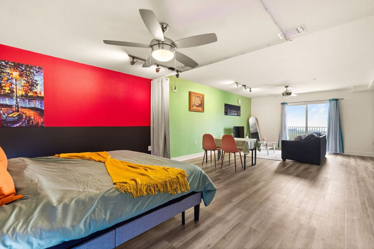 A modern hotel room with a bed, a desk, and a balcony.