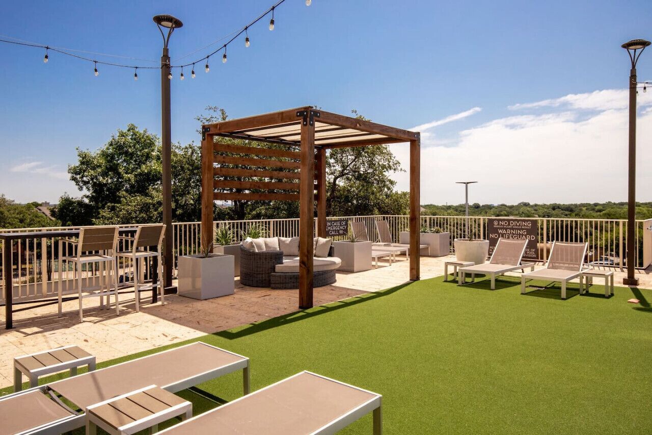 An outdoor patio with seating, a pergola, and a sign warning against diving.
