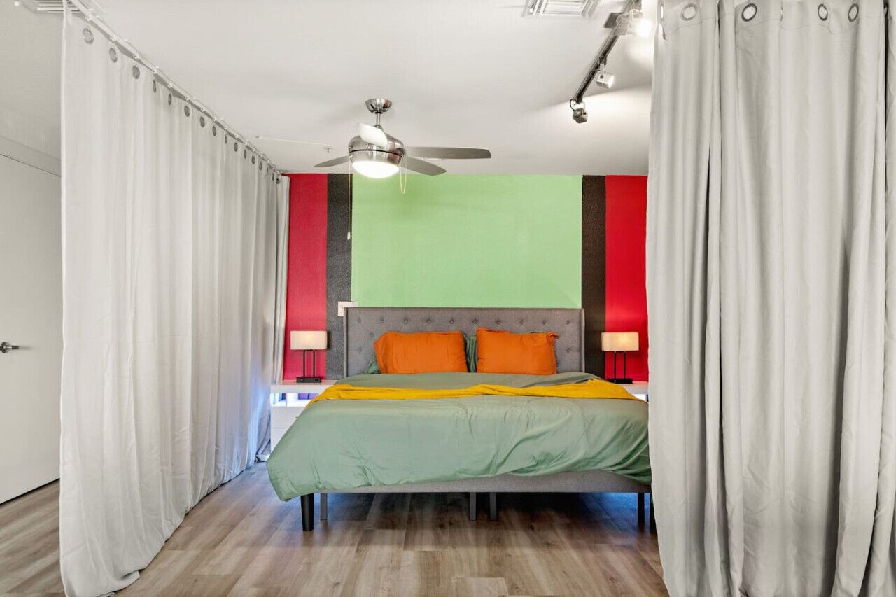 A bedroom with a bed, a ceiling fan, and curtains.