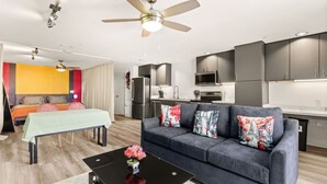 A modern living room with a grey sofa, a black coffee table, and a ceiling fan. - Six Flags/The Rim - Chic Modern Studio, King Bed (San Antonio)