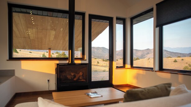 A modern living room with a fireplace, large windows, and a view of a desert landscape.