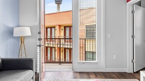 A room with a sliding glass door leading to a balcony with a view of a tower and buildings. - Vibrant Oasis-Tower/Pool View, King Bed+ Free Park (San Antonio)