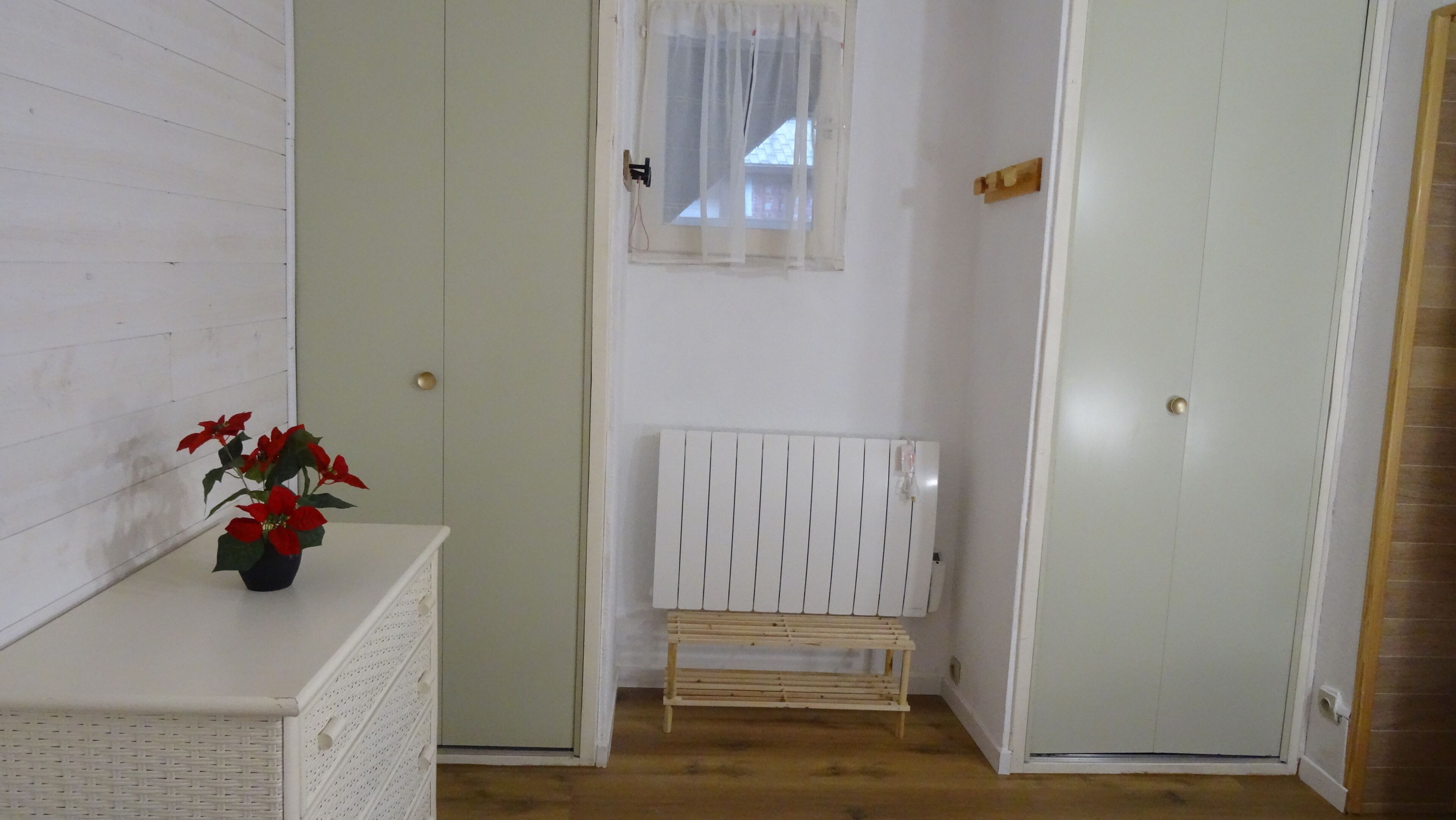 Una stanza con una parete bianca, una panca di legno, un termosifone e una porta.