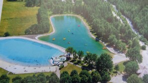 An aerial view of a park with a large lake, a playground, and a walking path. - In the heart of the resort and shopping district, a ground-floor apartment for 6 people (La Foux D'Allos)