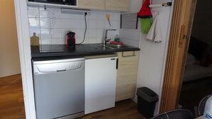 Een kleine keuken met een vaatwasser, een spoelbak en een kleine prullenbak.