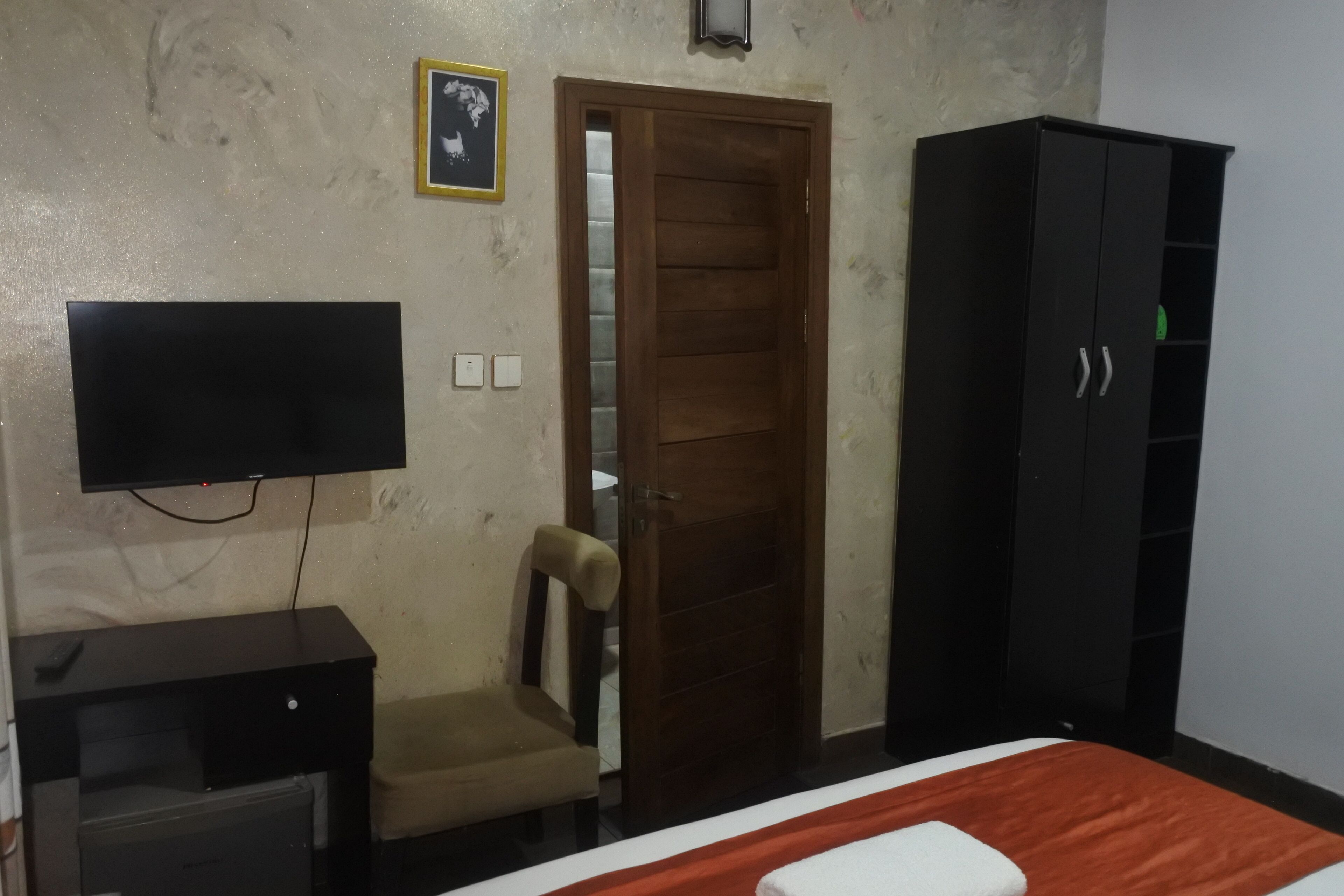 A bedroom with a bed, a television, a wardrobe, and a chair.