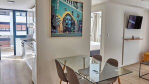 Ein modernes Wohnzimmer mit einem Glastisch, gemütlicher Sitzgelegenheit, einem Flachbildfernseher und einem großen Stadtbild.