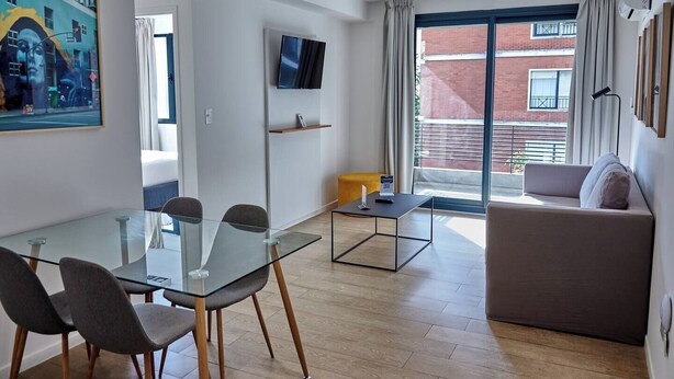 Ein modernes Wohnzimmer mit einem Glastisch, einer Couch und einem an der Wand befestigten Fernseher.