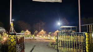 A gated entrance with a sign reading "Paws Time To Take A Pause" at night. - PAWS AT TIPESHWAR (Ghatanji)