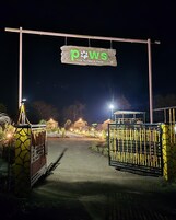 Una entrada con puerta y un letrero que dice "Paws Time To Take A Pause" de noche.