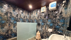 A bathroom with a floral-patterned wall, a shower, a toilet, and a sink. - PAWS AT TIPESHWAR (Ghatanji)