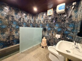 Un baño con un papel tapiz de motivos florales, una ducha, un inodoro y un lavabo.