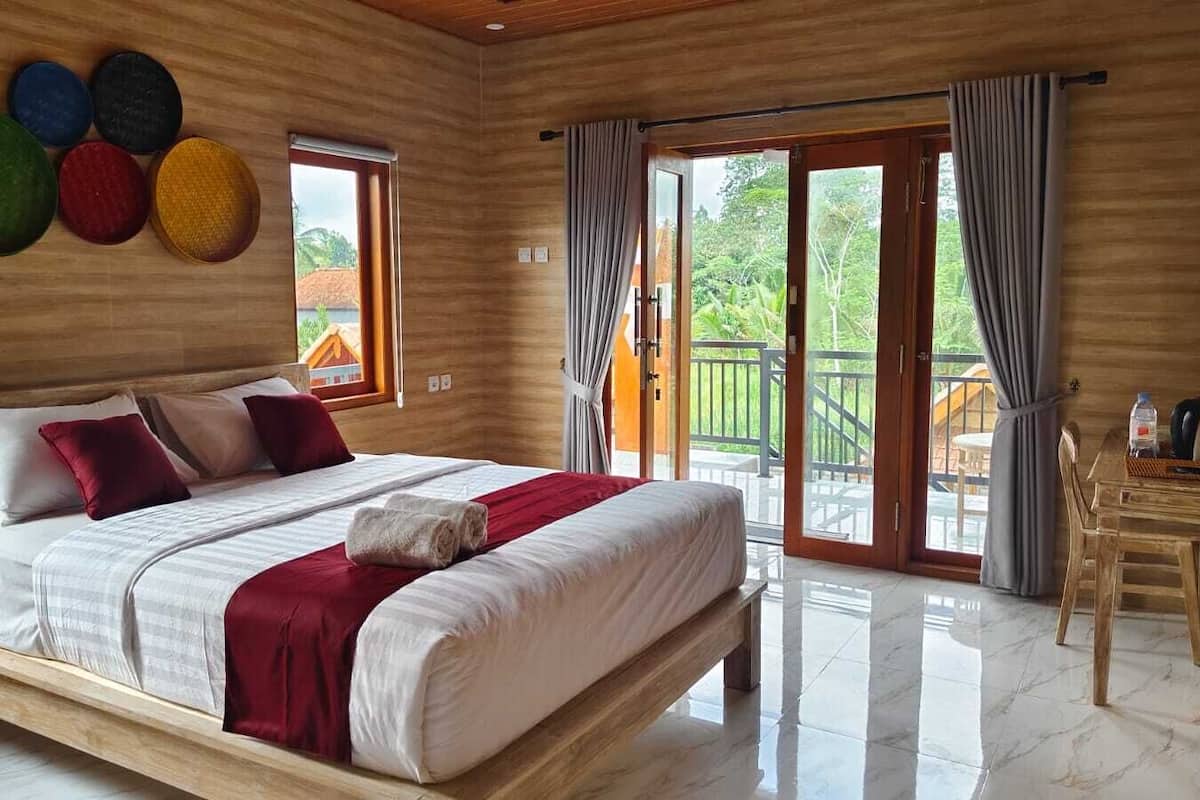 A spacious bedroom with a large bed, a wooden headboard, and a balcony with curtains.