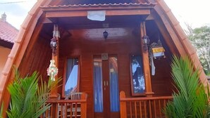 A wooden cabin with a pitched roof, a porch with railings, and a stone staircase leading to the entrance. - Green Pacing Lodge (Tembuku)