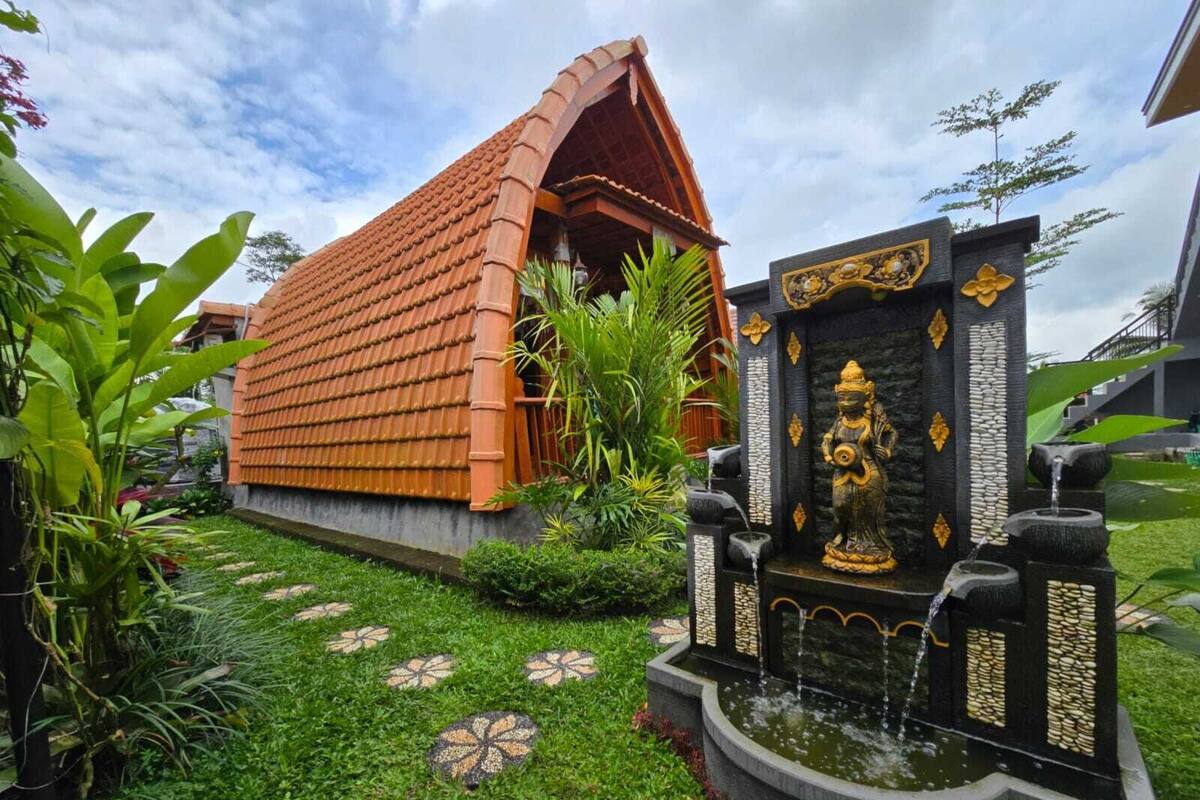 A traditional house with a tiled roof, a decorative statue, and a small water feature.