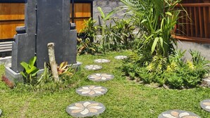 A garden area with a wooden pergola, stone steps, and tropical plants. - Green Pacing Lodge (Tembuku)