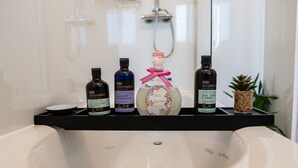 A bathroom with a white sink, a black shelf holding four bottles of bath products, and a small plant. - House - Sleeps 7 - Parking - Garden - Near Stn (Manchester)