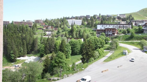 A residential area with houses, a road, and a small parking area.