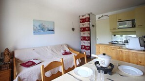 A cozy room with a bed, a dining table with plates and glasses, a microwave, and a kettle.
