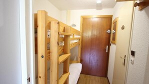 Un couloir étroit avec un lit superposé en bois et une porte.