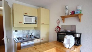 A compact kitchen with a microwave, stove, sink, and coffee maker.