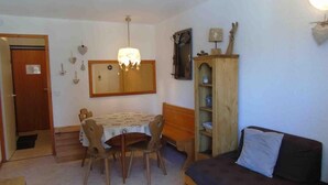 Um espaço de estar compacto com uma mesa de jantar, cadeiras, um sofá, um armário de madeira e um espelho na parede.