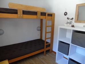 A bunk bed with a ladder, a white shelf unit with storage boxes, and a stuffed moose toy on the shelf.