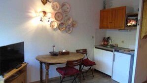A compact kitchen with a dining table, chairs, a refrigerator, and a microwave.