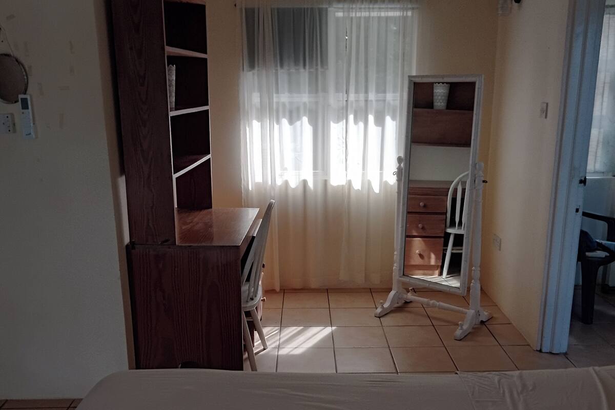 A bedroom with a bed, a wooden dresser, a mirror, and a wardrobe.