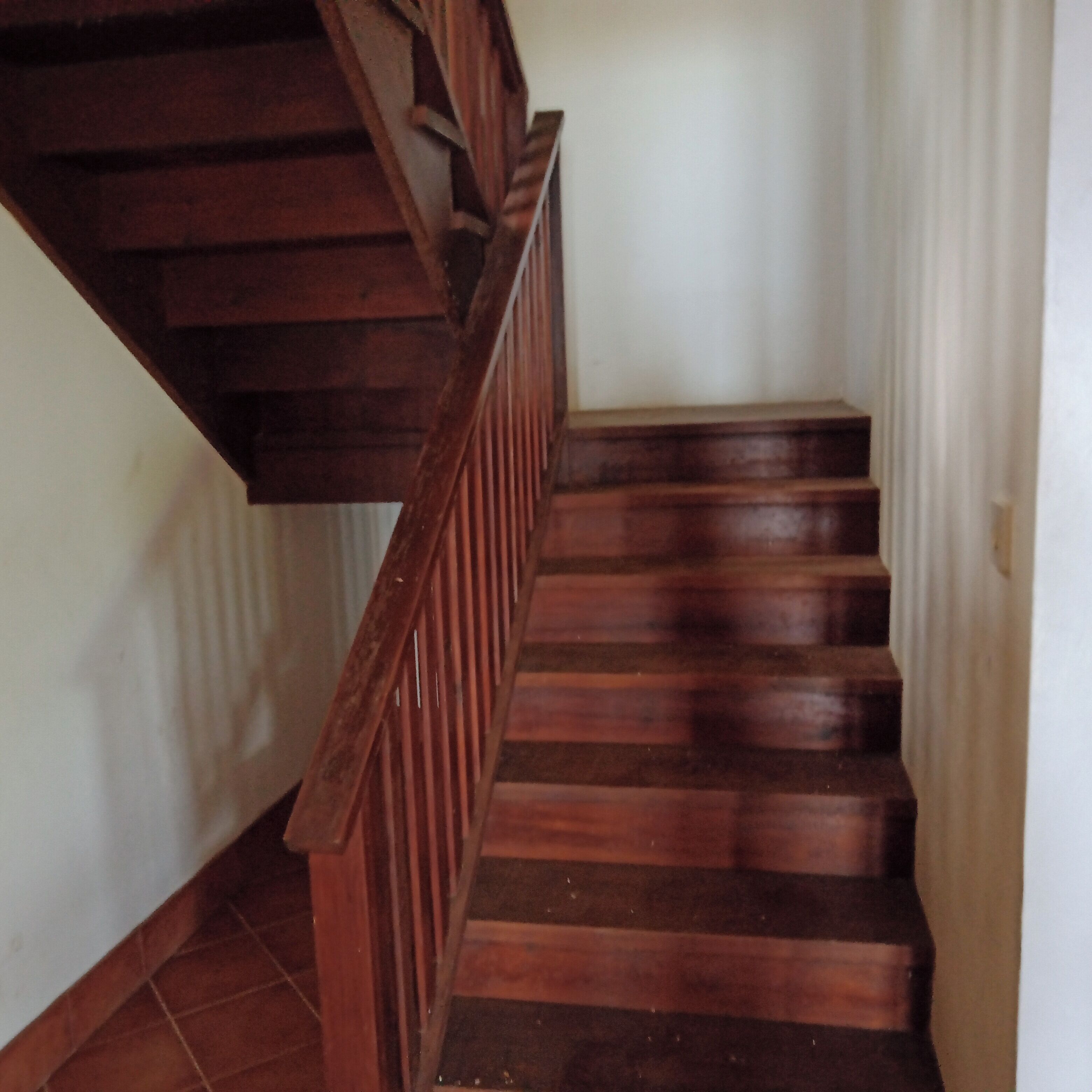 A wooden staircase with a handrail, leading to a landing.