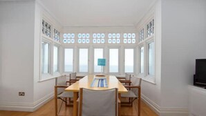 Uma sala de jantar com uma mesa comprida, cadeiras e um abajur azul.