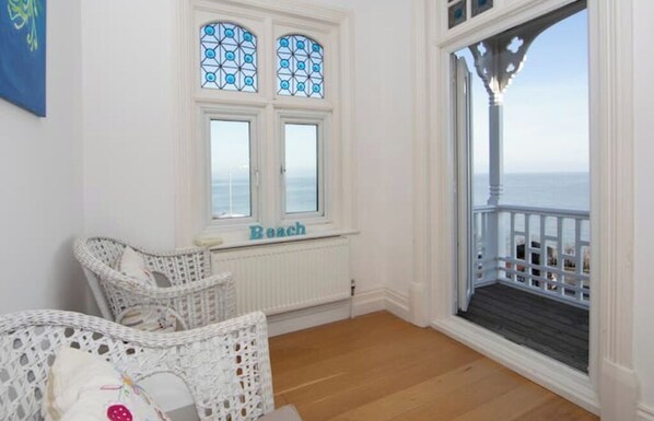 A room with a view of the sea, wicker furniture, and a window labeled "Beach".