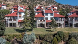 A cluster of stone buildings with red roofs, arranged in a courtyard with a mountain backdrop. - Sky Shades Villa in Arachova (Arachova)