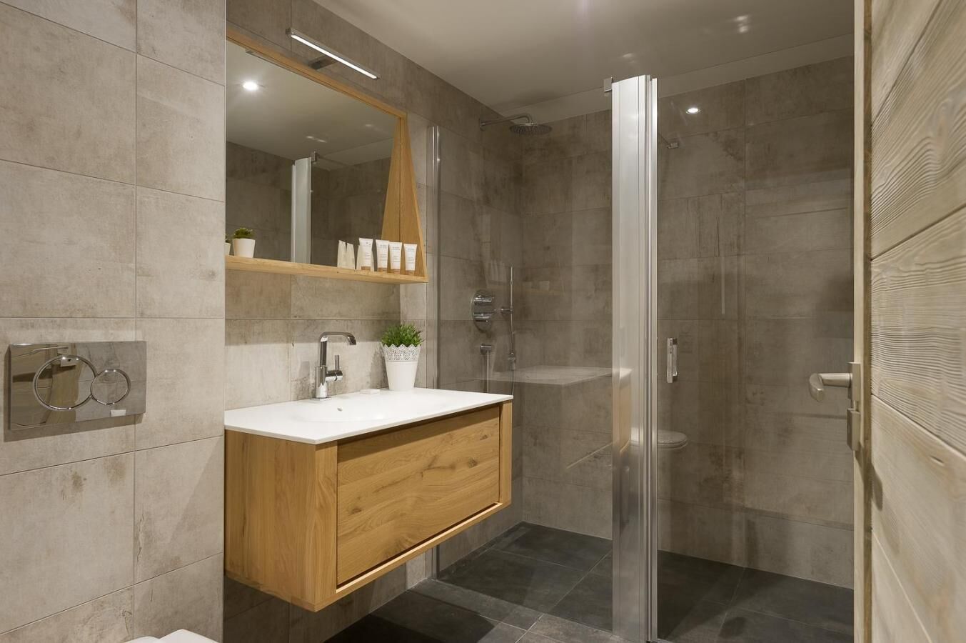 Un baño moderno con tocador de madera, cabina de ducha de vidrio y un espejo grande.