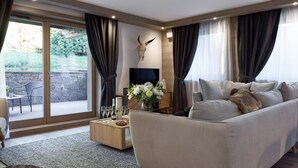 A modern living room with a sofa, a coffee table, a TV, and a stone wall. - Wifi, 200m from ski slopes, 1st floor, sauna, hammam, terrace, parking, tv, 109m², Les Gets (Les Gets)