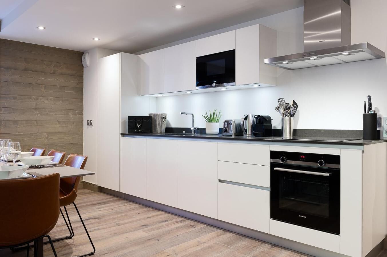 A modern kitchen with white cabinetry, a built-in oven, and a microwave.
