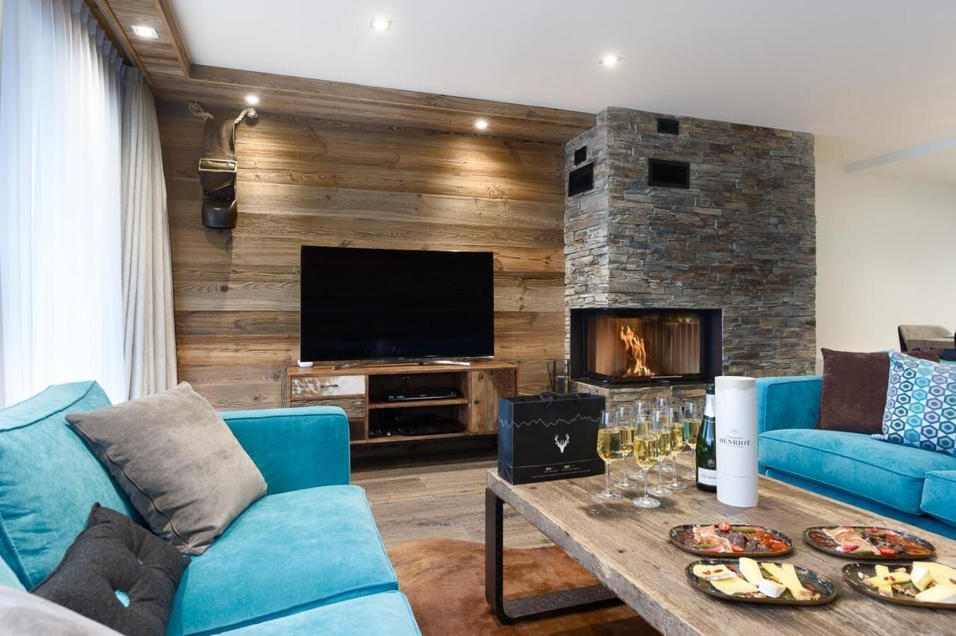 A modern living room with a stone fireplace, a flat-screen TV, and a wooden wall.