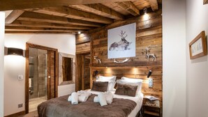 Un dormitorio con techo de madera, una cama con manta marrón, una obra de arte de un ciervo en la pared y cabecero de madera.