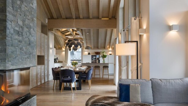 A modern interior with a stone fireplace, a dining area, and a cozy seating area with a fur throw. - Wifi, resort center, 3rd floor, view mountain, sauna, hammam, terrace, balcony, fireplace or stove (Les Gets)
