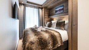 A modern hotel room with a large bed, wooden headboard, and a painting of a lake. - Wifi, 200m from ski slopes, Ground floor, terrace, fireplace or stove, parking, tv, 110m², Les Gets (Les Gets)