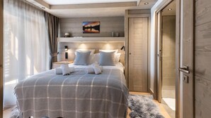 A modern bedroom with a large bed, a headboard with integrated lighting, a painting above the bed, and a wooden door. - Wifi, 200m from ski slopes, 2nd floor, balcony, parking, tv, 70m², Les Gets (Les Gets)
