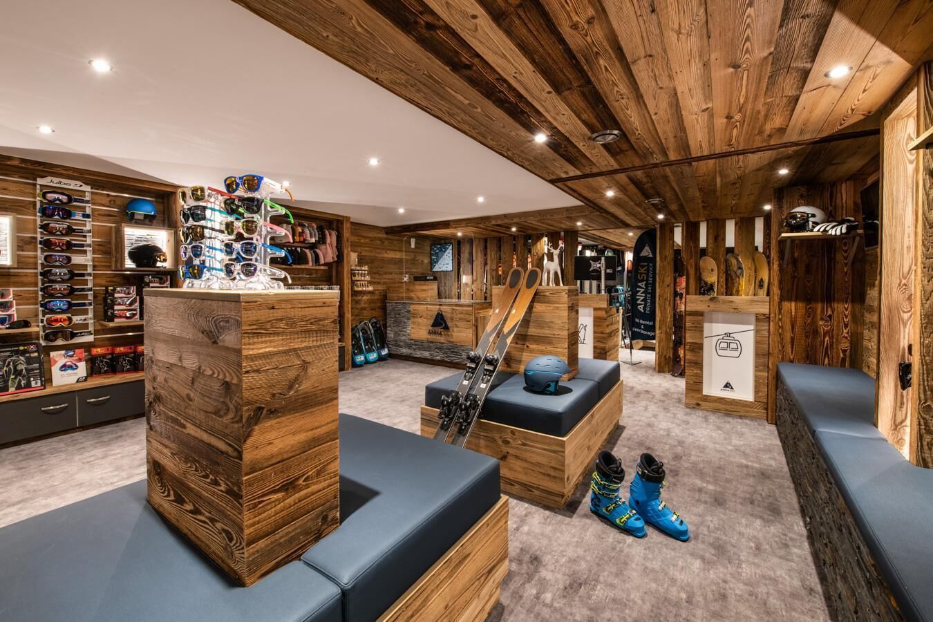 A ski lodge interior with wooden walls, ski equipment, and seating areas.