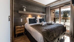 Ein modernes Schlafzimmer mit einem großen Bett, einem Holzkopfstück und Blick auf einen Balkon.