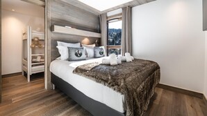 Ein modernes Schlafzimmer mit einem großen Bett, integriertem Kleiderschrank und Blick ins Freie.