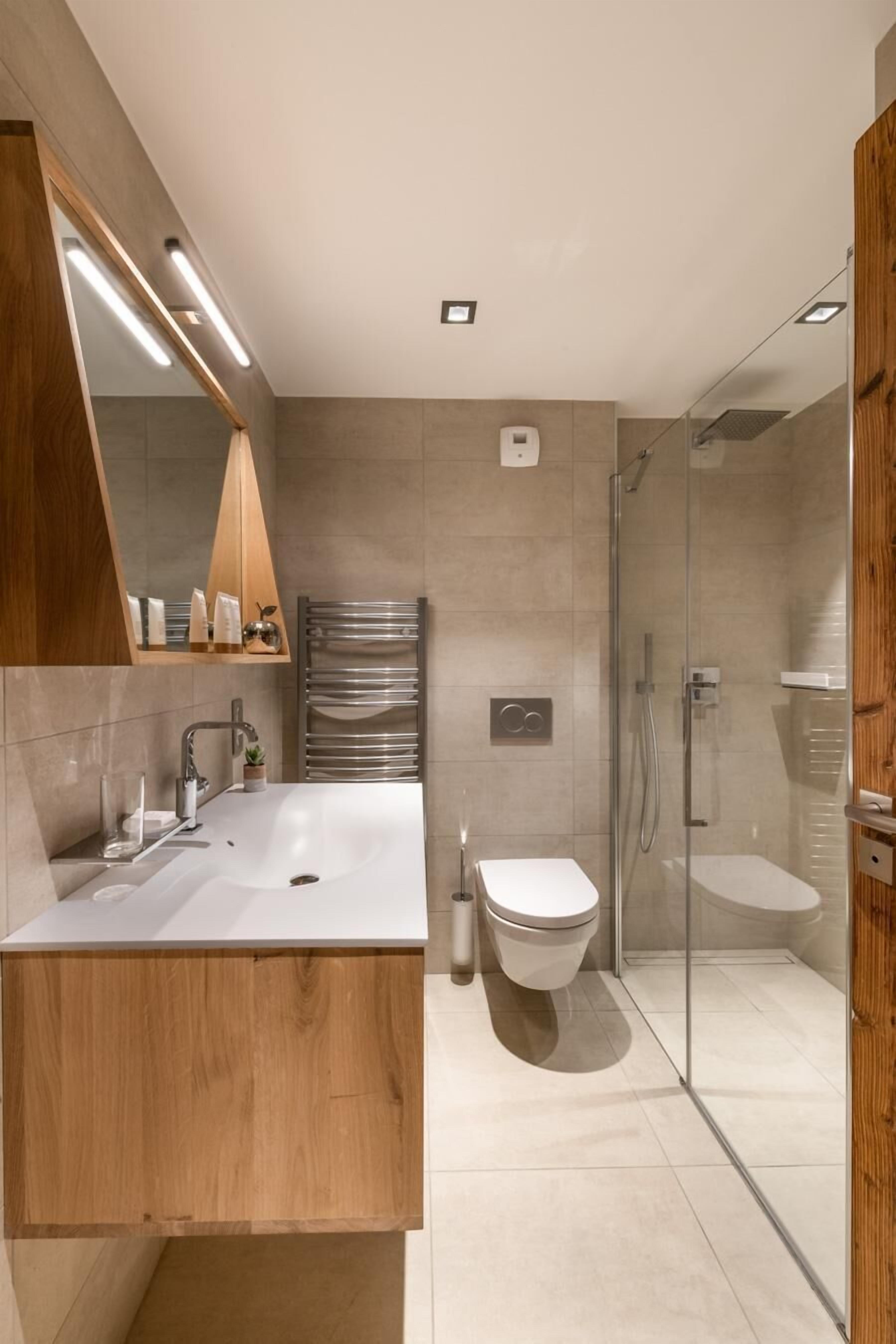 A modern bathroom with a large sink, mirror, and glass shower enclosure.